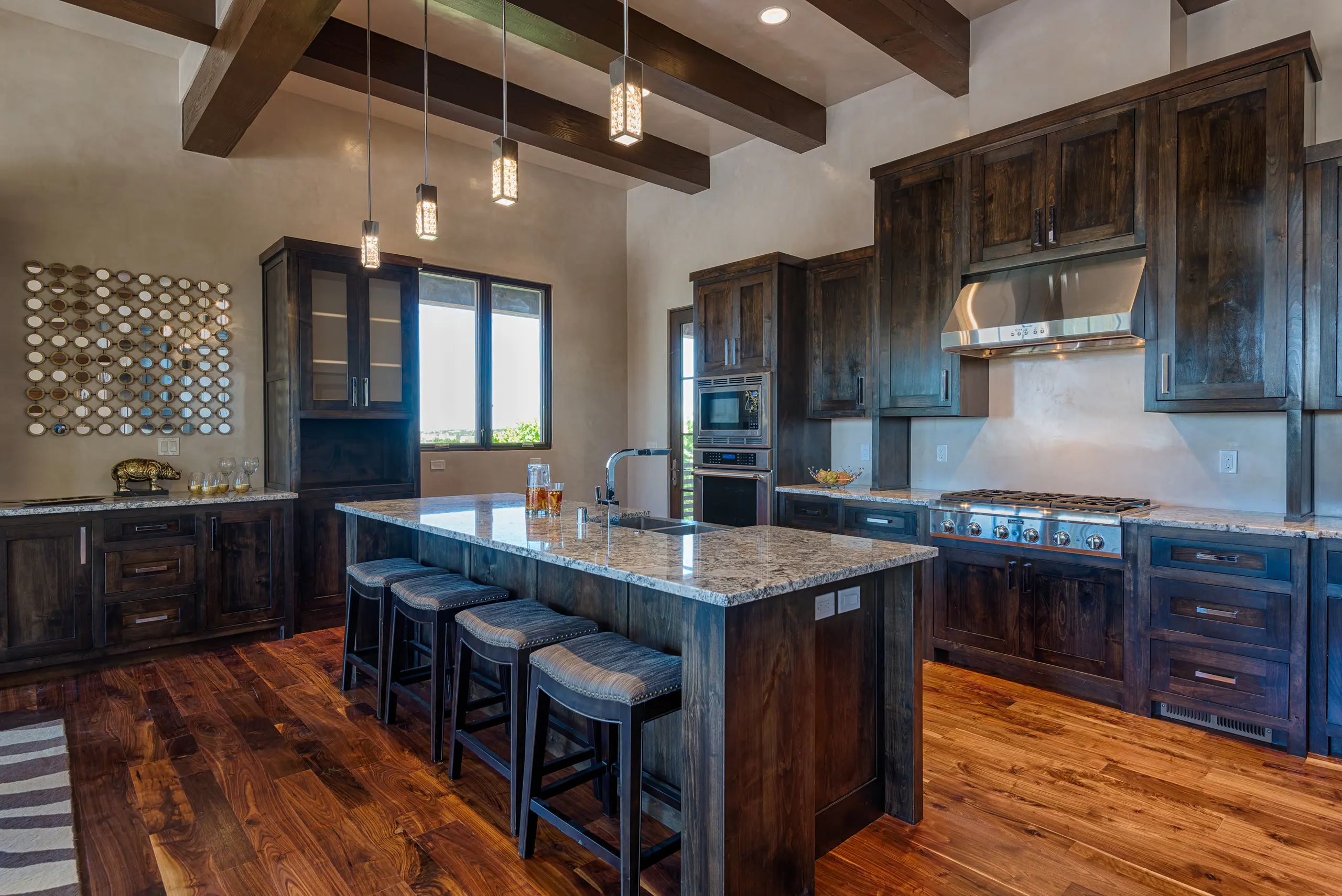 Rustic kitchen with wooden beams, dark cabinetry, and a large island with seating.